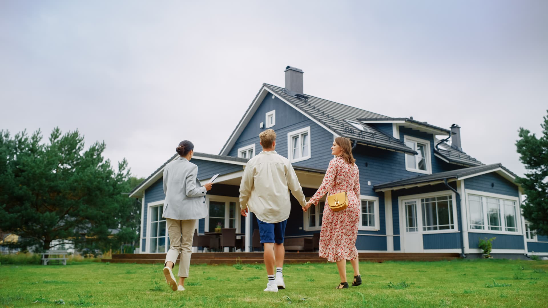 Real estate professional walking buyers up to a home