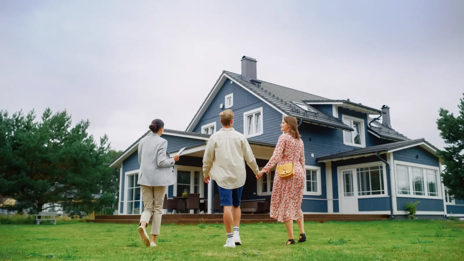 Real estate agent walking a couple toward a home while reviewing an independent RooFax roof inspection report